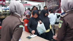 Seorang ibu mencelupkan jarinya setelah berbelanja di pasar murah yang dilaksanakan di halaman kejaksaan negeri Sumedang. Selasa (12/8/2025)