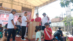 Keterangan: Kepala Desa Sudipayung, Yusuf, saat menyerahkan hadiah jalan sehat kepada warga, di Halaman Baldes Sudipayung, Minggu 31/08/2025. (Roni/Jateng Memanggil)