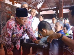 Pj Bupati Kudus berbincang dengan anak penyandang disabilitas usai menerima bantuan kursi roda. (ist)