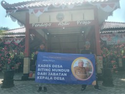 Warga Desa Biting membentangkan spanduk berisi tuntutan untuk kepala desa (Memanggil.co/Dian Tega Pratama)