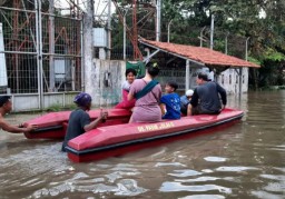 Sejumlah warga melintas genangan air menggunakan perahu karet saat hendak mengungsi ke tempat aman (Memanggil.co/Antara)