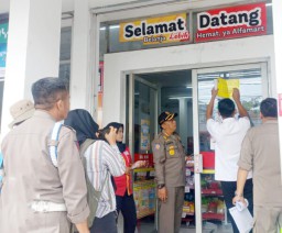 Petugas saat memasang tanda stiker bangunan sudah berizin di beberapa toko modern berjejaring, Senin (10/02/2025) (Memanggil.co/Ist)