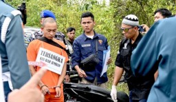 Penyidik menyaksikan tersangka Jumran (baju oranye) memperagakan adegan pembunuhan jurnalis di tempat kejadian perkara (TKP) (Memanggil.co/Antara/Tumpal Andani Aritonang)