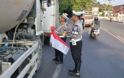 Anggota Polres Tuban ketika menyerahkan bendera merah putih kepada sopir yang melintas di jalur Tuban.