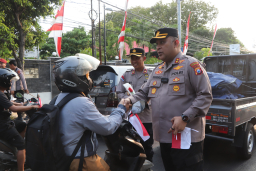 Kapolres Tuban AKBP William Cornelis Tanasale, ketika membagikan bendera merah putih kepada masyarakat.